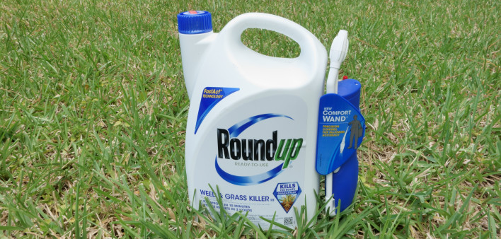 A container of Roundup Weed and Grass Killer on a grass lawn.