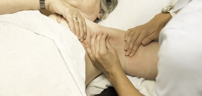 A woman's swollen arm is palpated by a doctor