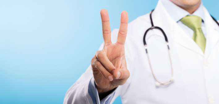 a doctor in white jacket making a peace sign with his fingers