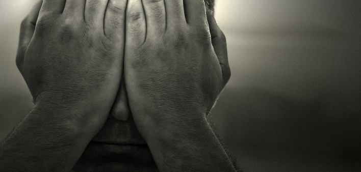 a black and white image of a man holding his hands over his face