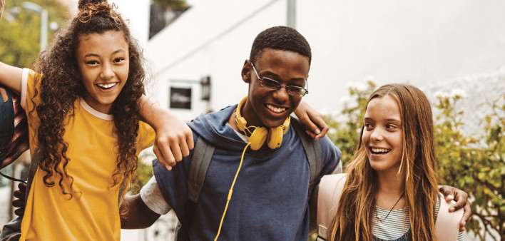 group of young kids walking arm and arm laughting