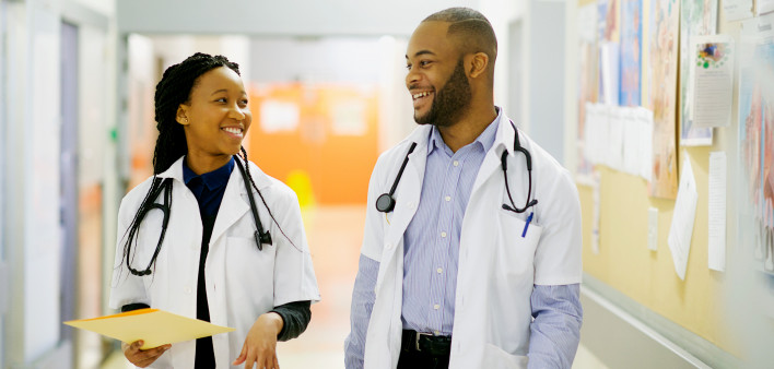 Two young African-American doctors having a laugh in the corridor walking Cape Town South