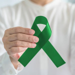 hand with green ribbon cerebral palsy and liver cancer awareness