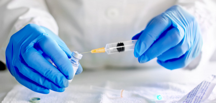 Doctor fills injection syringe with vaccine