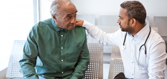 Doctor consoling sad senior male patient