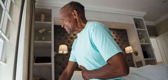 man in bed with belly pain holding stomach