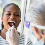 Doctor performing Covid-19 tests on patient while wearing protective gear stock photo