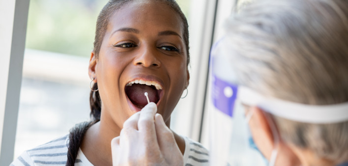 Doctor performing Covid-19 tests on patient while wearing protective gear stock photo