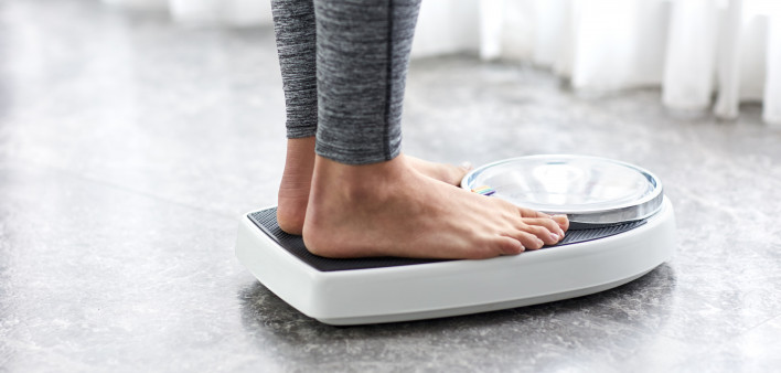 Young healthy girl on home scales