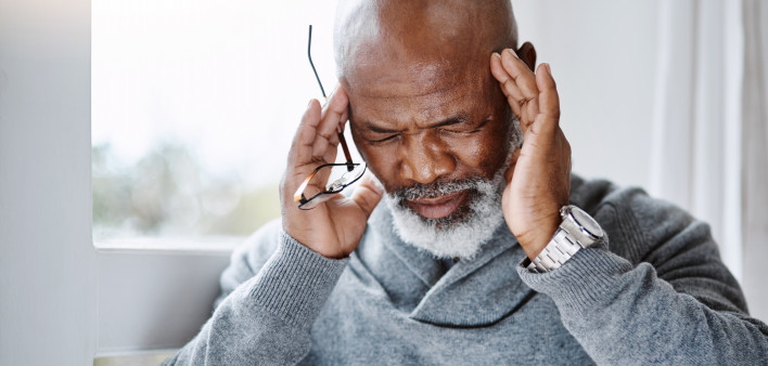 Shot of a handsome senior man suffering with a headache at home