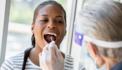 Doctor performing Covid-19 tests on patient while wearing protective gear stock photo
