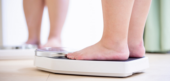 plus size asian girl look mirror and measure her weight by scale