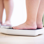 plus size asian girl look mirror and measure her weight by scale