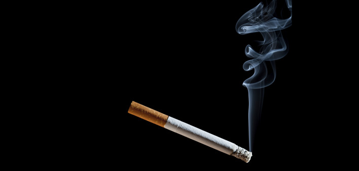 Cigarette with blue smoke on black background