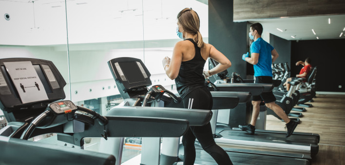 Instructor and student workout at gym after pandemic reopening. They running on treadmill