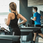 Instructor and student workout at gym after pandemic reopening. They running on treadmill