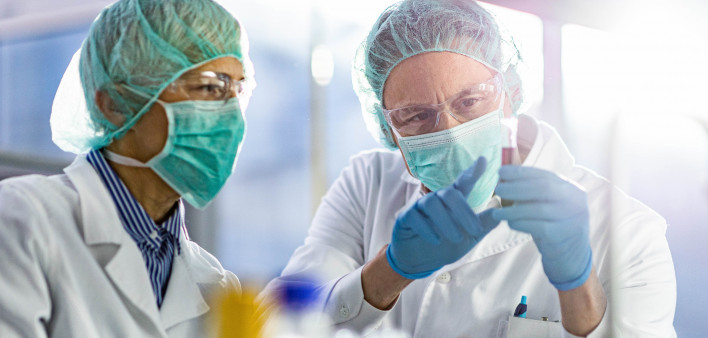 Two scientists cooperating while examining antiviral drug in a test tube at laboratory