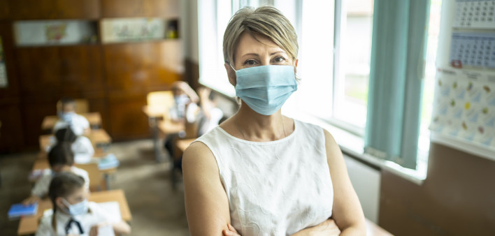 Young elementary teacher wearing a protective face mask at school.