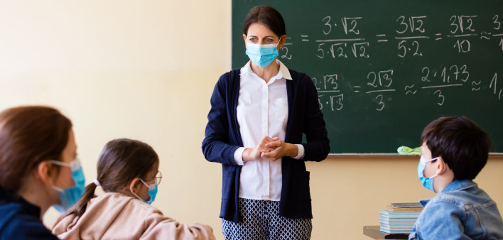 teacher wearing mask in classroom child wearing mask covid-19