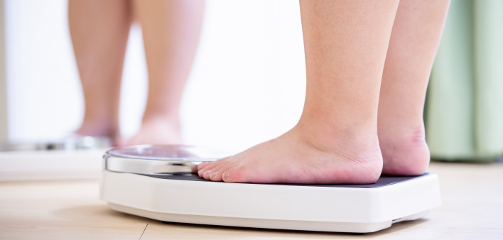 plus size asian girl look mirror and measure her weight by scale