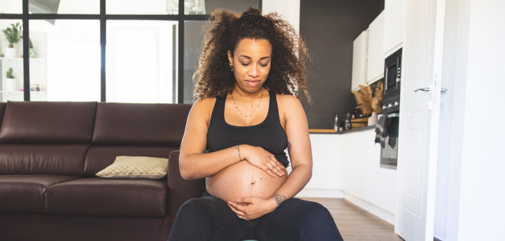 Pregnant woman practicing Yoga with online video class during Coronavirus pandemic lockdown.