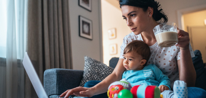 Young modern mother with a baby using laptop at home