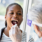 Doctor performing Covid-19 tests on patient while wearing protective gear stock photo